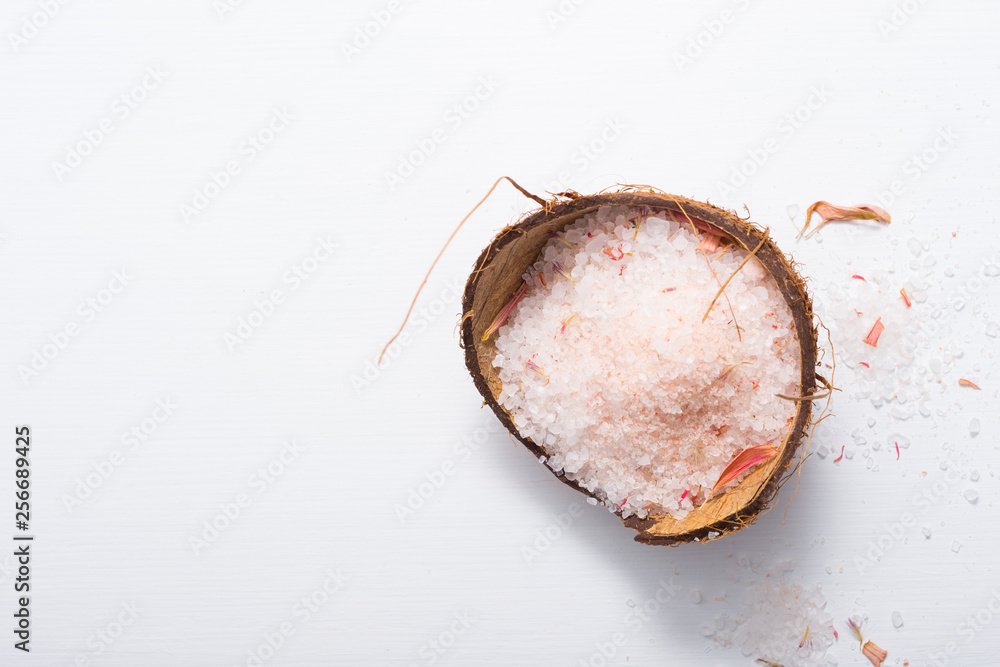 pile of pink bath salt at coconut shell bowl, white wood table pile of pink bath salt at coconut shell bowl, white wood table
