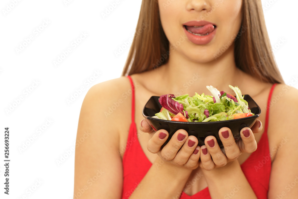 Cropped close up of a beautiful healthy woman licking her lips seductively holding a bowl of fresh delicious salad isolated. Sexy fitness female hungry for vitamin salad. Dieting, nutrition concept Cropped close up of a beautiful healthy woman licking her lips seductively holding a bowl of fresh delicious salad isolated. Sexy fitness female hungry for vitamin salad. Dieting, nutrition concept