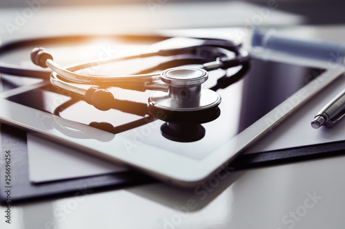 Healthcare and technology concept - tablet and stethoscope on white table photo