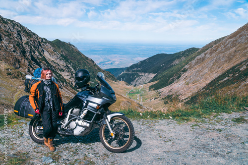 Young girl with adventure motorcycle. woman rider. Top of the mountain road. Motorbike vacation. Travel and active lifestyle Transfagarasan Romaia