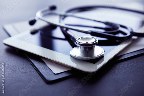 Medical equipment on table. Blue stethoscope and tablet on white background.