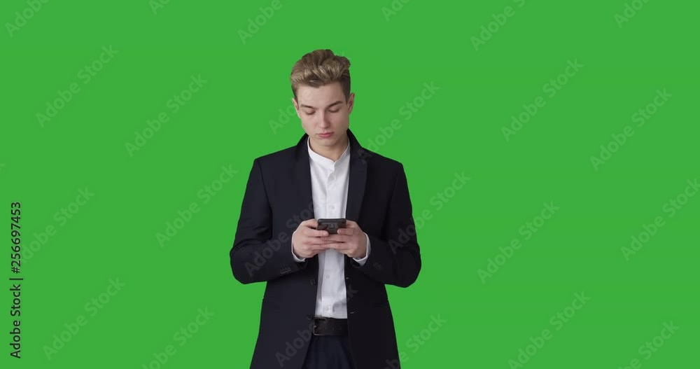 Handsome businessman text messaging on mobile phone over green chroma key background Handsome businessman text messaging on mobile phone over green chroma key background
