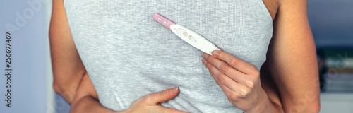 Back view of happy couple hugging while woman hand holding positive pregnancy test