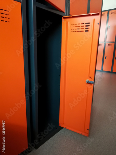 Closeup of locker room situated in work place. Orange lockers, storage for workers.