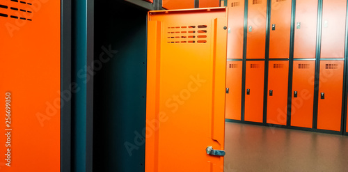 Closeup of locker room situated in work place. Orange lockers, storage for workers.