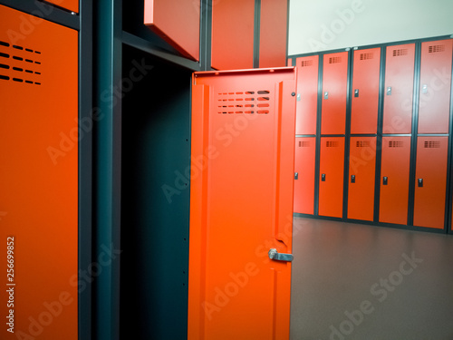 Closeup of locker room situated in work place. Orange lockers, storage for workers.