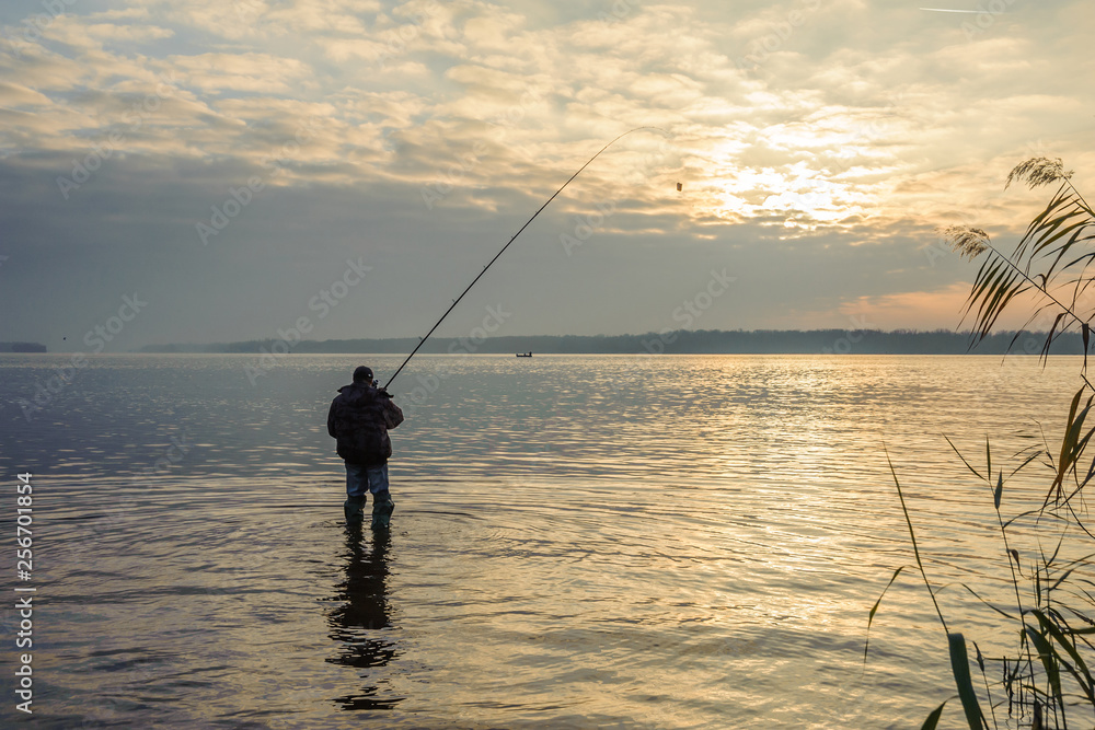 Man catches fish in the water against the sky