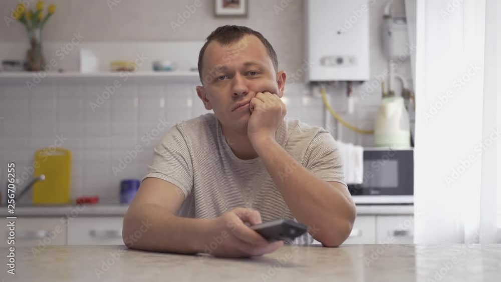 Bored Man Watching Tv Sitting By Table In Kitchen At Home Alone Bored Man Watching Tv Sitting By Table In Kitchen At Home Alone