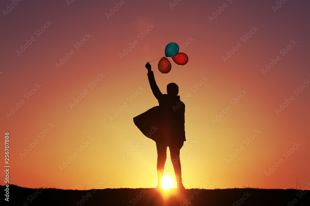 The girl with colorful balloons on the background of the sunset