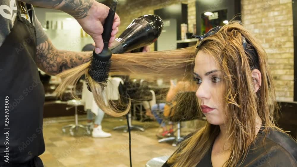 Caucasian woman having her hair styled in a hipster barbershop themes of hairstylist pampering glamour haircare Caucasian woman having her hair styled in a hipster barbershop themes of hairstylist pampering glamour haircare