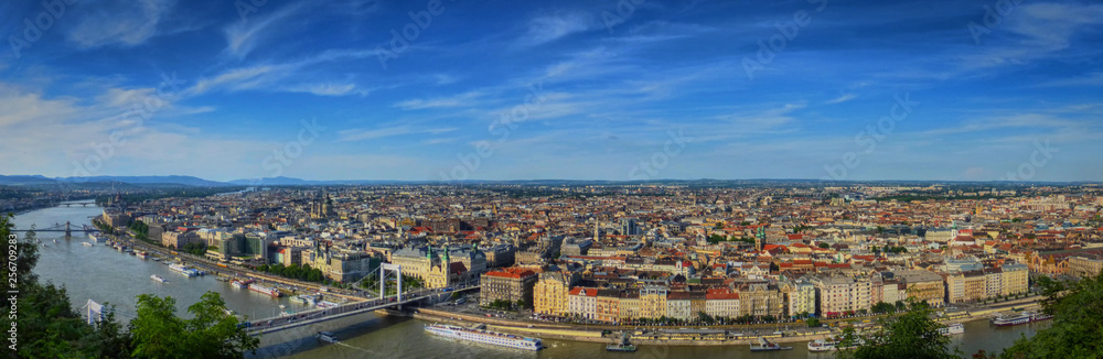 A panoramic view of the eastern half of Budapest (Pest) with the Danube river, a few bridges, and lots of boats and buildings