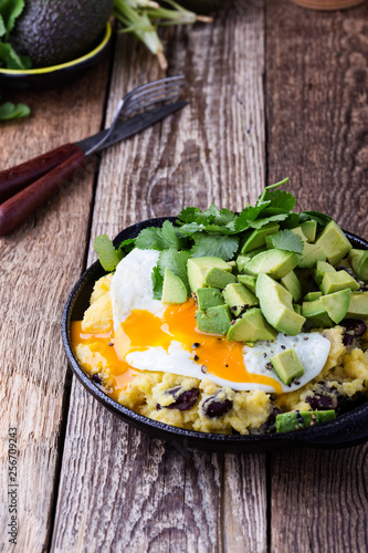 Healthy vegetarian  brunch with  grits, black beans,  avocado topped fried egg