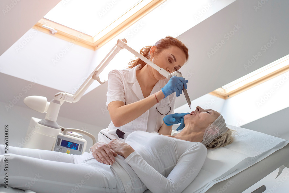 Senior woman getting laser face treatment in medical center Senior woman getting laser face treatment in medical center