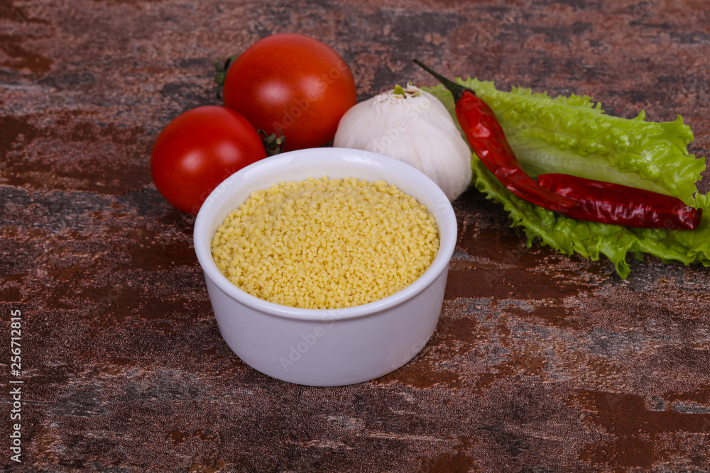 Raw couscous in the bowl served salad leaves, tomato and pepper Raw couscous in the bowl served salad leaves, tomato and pepper