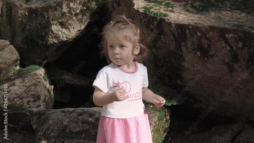 Portrait of little girl near big stones in forest, which looks for something, close-up Portrait of little girl near big stones in forest, which looks for something, close-up
