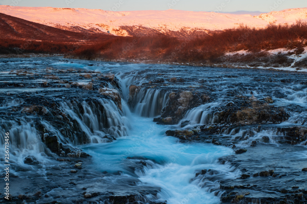 The famous blue water of Bruarfoss waterfall in Iceland during a winter sunrise. 