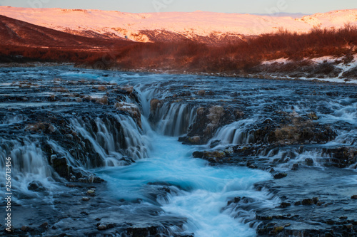 The famous blue water of Bruarfoss waterfall in Iceland during a winter sunrise. 