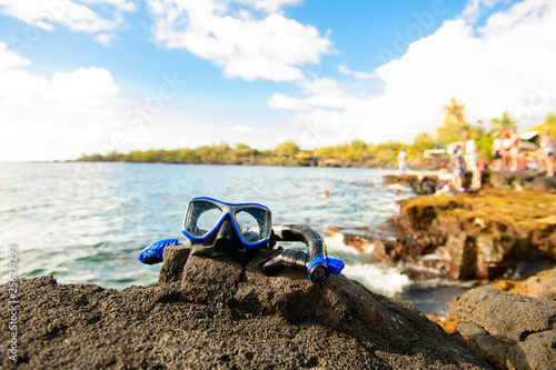 Photography A Colorful snorkle or diving mask located on the rocks with snorkling group on t
