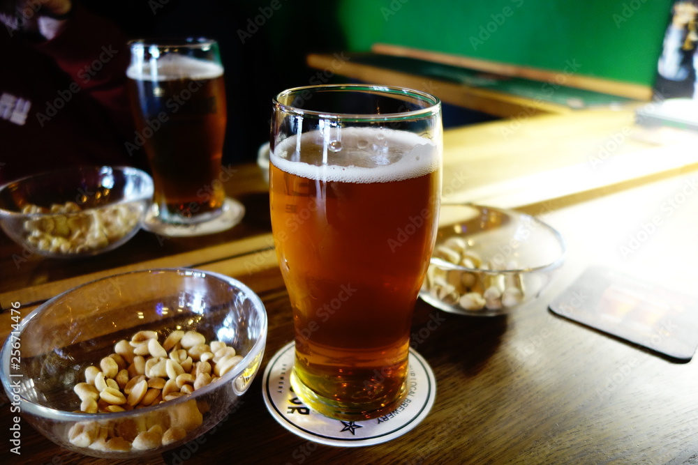 Pale IPA beer in a pint glass with salty peanuts and pistachios Pale IPA beer in a pint glass with salty peanuts and pistachios