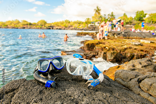 Photography A Colorful snorkle or diving mask located on the rocks with snorkling group on t