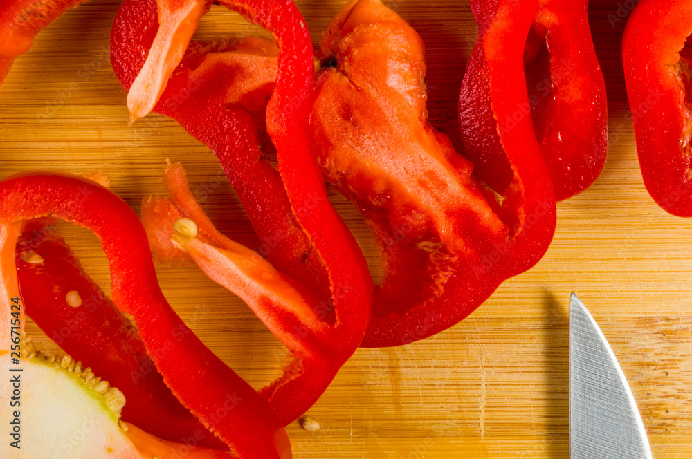 sliced fresh red paprika, bell pepper on bamboo cutting board sliced fresh red paprika, bell pepper on bamboo cutting board