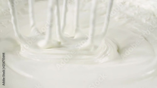 Whipping white cream with a mixer in slow motion side view photo