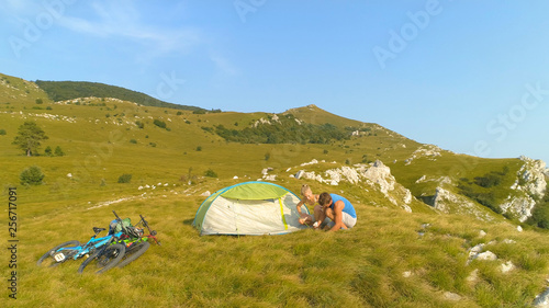 AERIAL: Man and his girlfriend preparing a tent to spend the day in mountains.