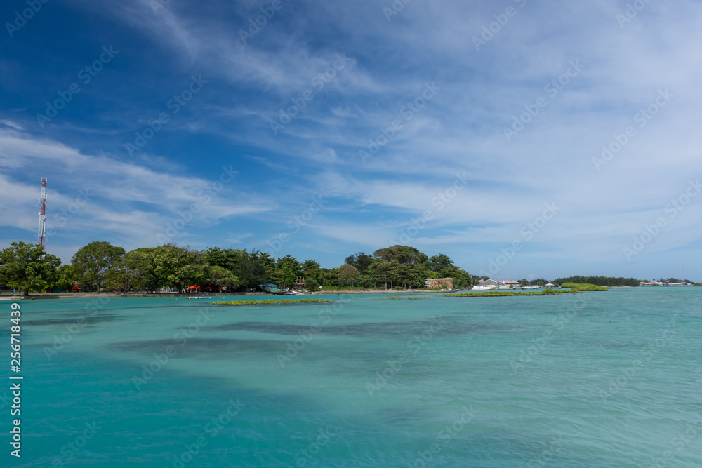 A beautiful panoramic of Kepala Island with clear sky and turquoise water taken from speed boat at Thousand Islands, Indonesia