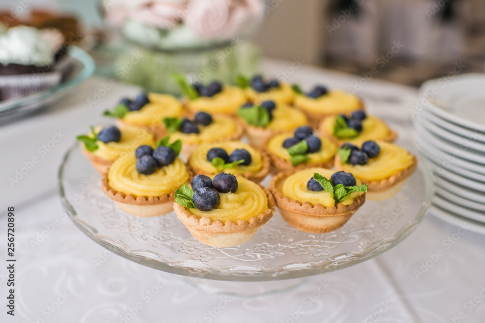 Tasty tartlets with whipped cream and blueberries on table in the restaurant
