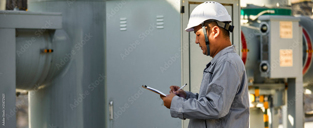 Asian engineer recording electrical box data for power station
