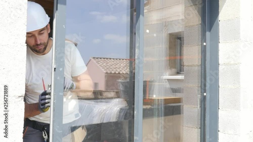 handsome young man installing bay window in a new house construction site