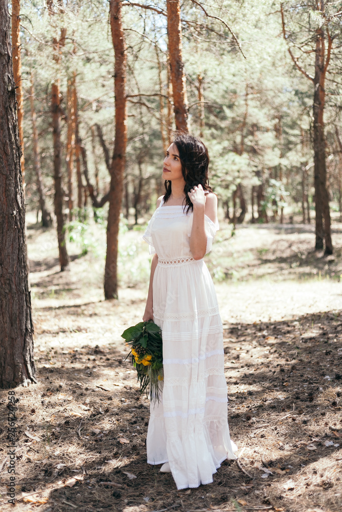Wedding walk in the pine forest. Sunny day. Wedding couple in the forest. Beautiful Bride and groom on a walk. White wedding dress. Bouquet of peonies and hydrangeas.