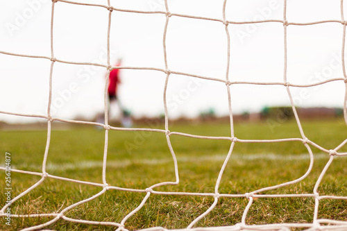 Football goal net and a player warming up