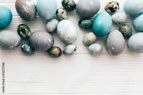 Stylish Easter eggs flat lay on white wooden background with space for text. Modern easter eggs painted with natural dye in blue and grey marble. Happy Easter concept, greeting card mockup