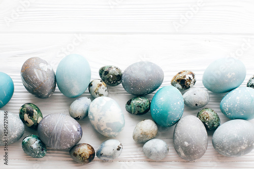 Stylish Easter eggs border flat lay on white wooden background with space for text. Modern easter eggs painted with natural dye in blue and grey marble. Happy Easter, greeting card mockup
