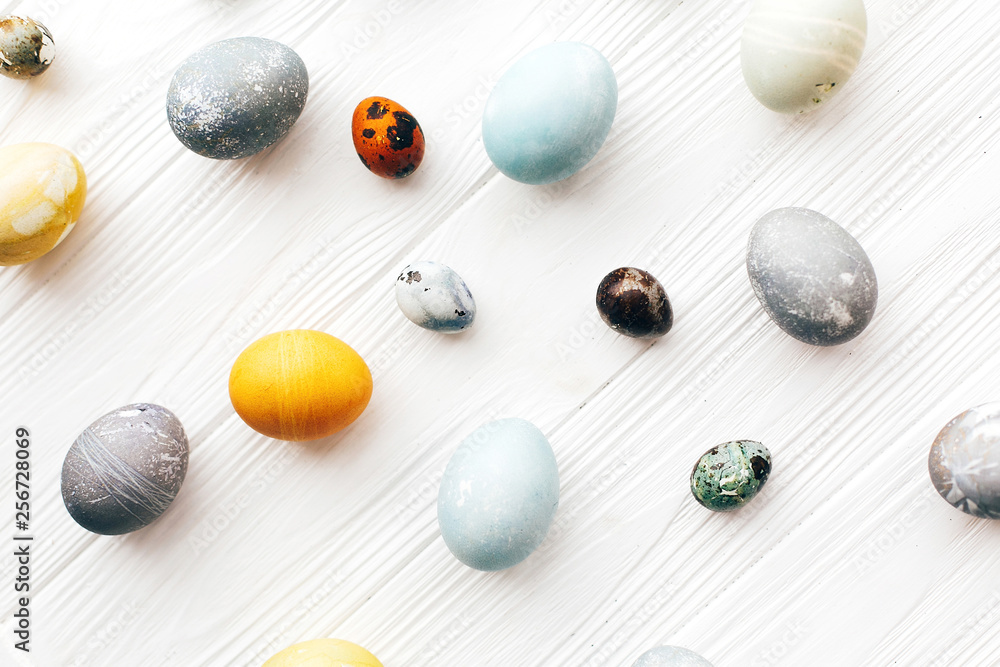 Happy Easter greeting card. Stylish Easter eggs flat lay on white wooden background. Modern easter eggs painted with natural dye in yellow,blue,green,grey colors. Creative pattern Happy Easter greeting card. Stylish Easter eggs flat lay on white wooden background. Modern easter eggs painted with natural dye in yellow,blue,green,grey colors. Creative pattern