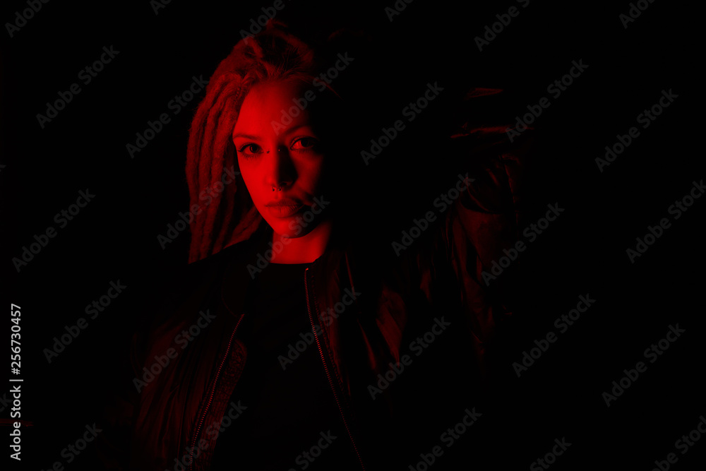 beautiful girl in the light of neon colored lamps light red on black background