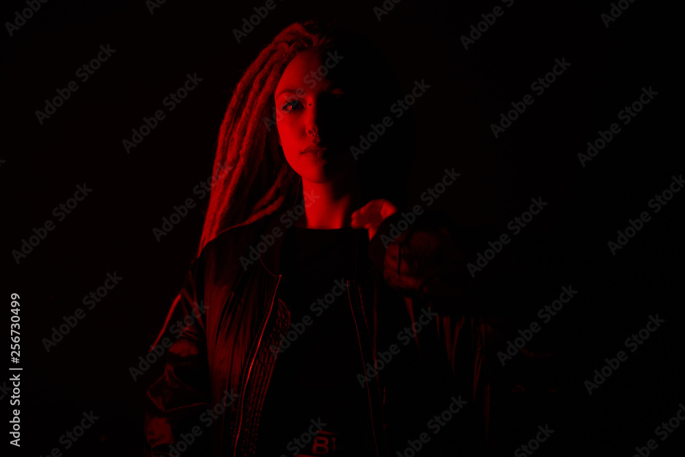 Naklejka premium beautiful girl in the light of neon colored lamps light red on black background