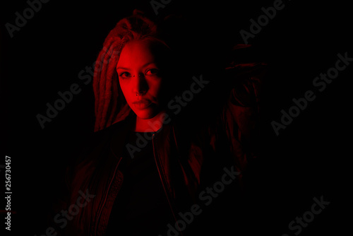 beautiful girl in the light of neon colored lamps light red on black background