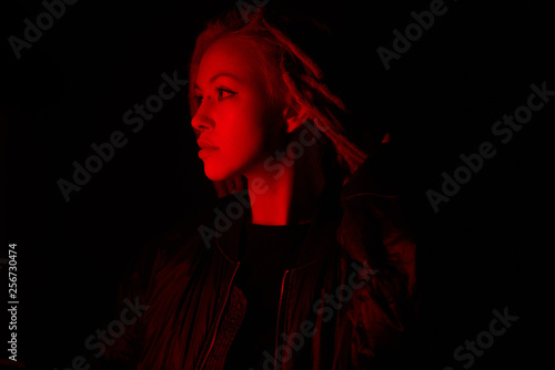 beautiful girl in the light of neon colored lamps light red on black background