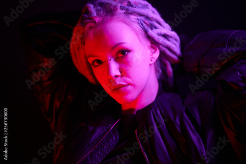 beautiful girl in the light of neon colored lamps light purple red on black background