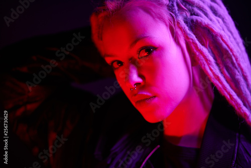 beautiful girl in the light of neon colored lamps light purple red on black background