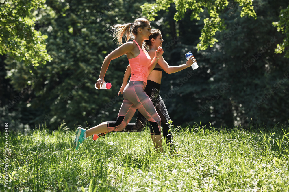 Two young female friends jogging in the nature.Spring time activity.