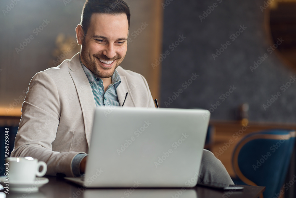 Happy businessman reading an e-mail on a computer while having coffee break in a cafe Happy businessman reading an e-mail on a computer while having coffee break in a cafe