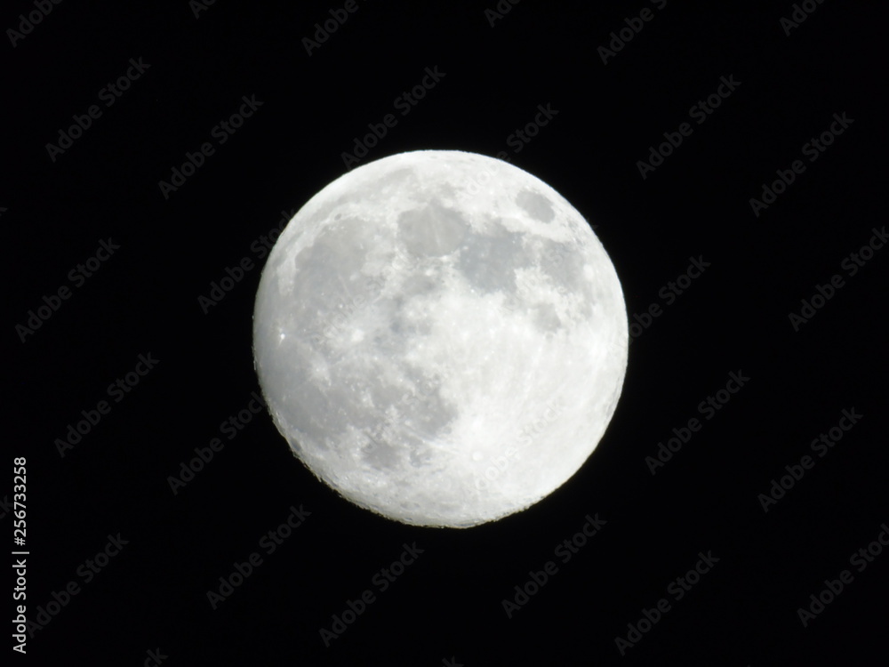 Genova, Italy - 03/20/2019: An amazing photography of the full moon over the city of Genova by night with a great clear sky in background and some stars