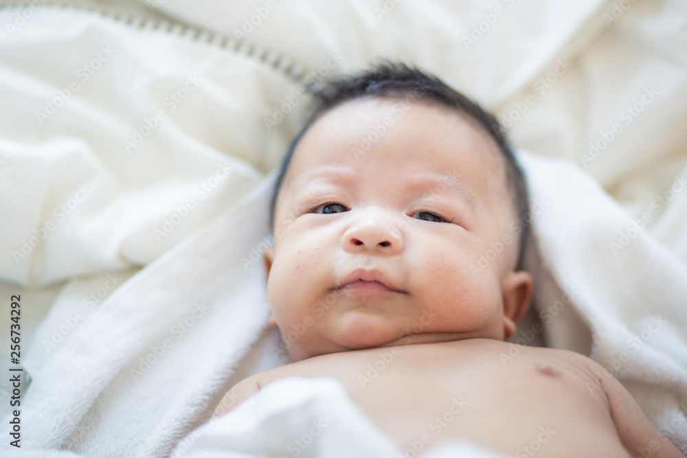 Funny infant baby boy lying on bed after wake up Funny infant baby boy lying on bed after wake up