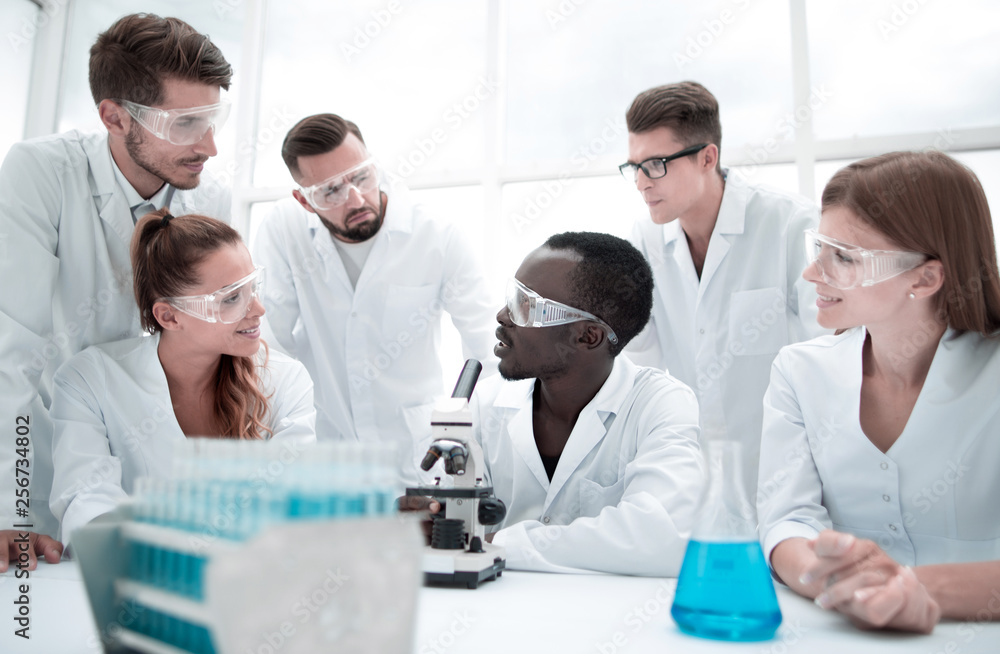 Fototapeta premium Focused and serious female and male chemists in lab coats and safety goggles making experiments