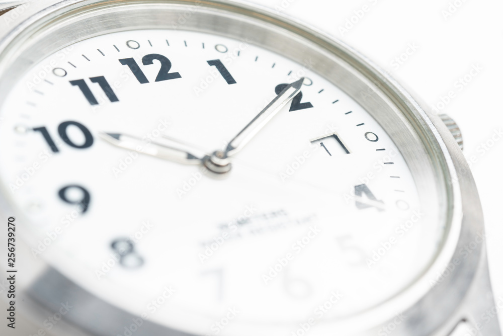 A macro shot with selective focus of the white dial of a round watch face with big numbers. A macro shot with selective focus of the white dial of a round watch face with big numbers.