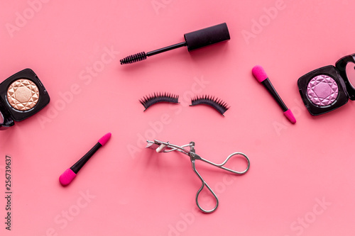 decorative cosmetic set with lash curler and mascara on pink woman desk background top view