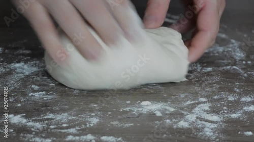 Close up of  hands of a man who knead dough on a table.